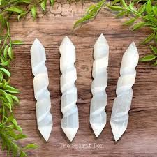 Four white selenite wands with spiral carvings.