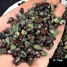 Green and red gemstone chips in a hand.