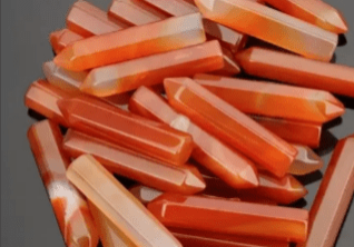 A pile of orange carnelian crystal wands.