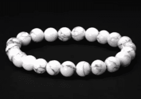 White gemstone bead bracelet on black background.