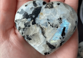 Heart-shaped moonstone crystal with black inclusions.