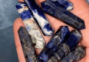 Hand holding a pile of blue sodalite points.