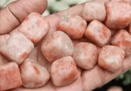 Hand holding a pile of orange stones.