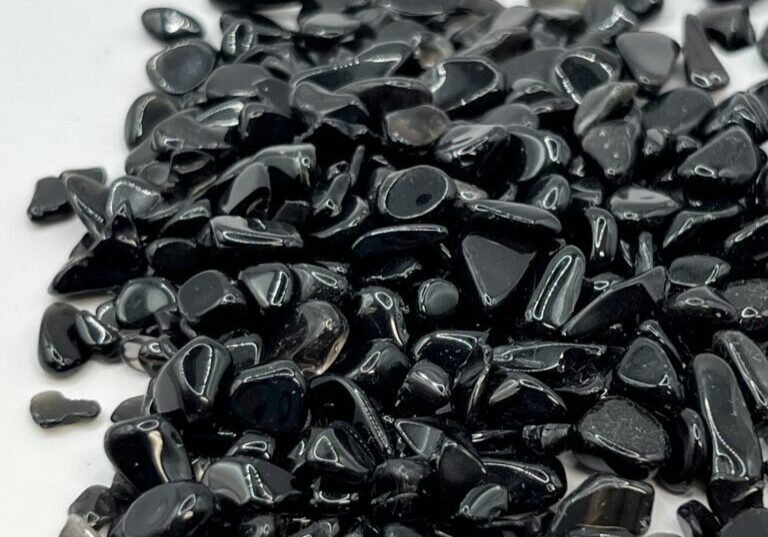 Black obsidian gemstone chips on white.