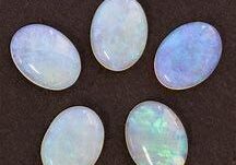 Five oval-shaped white opals on a dark surface.